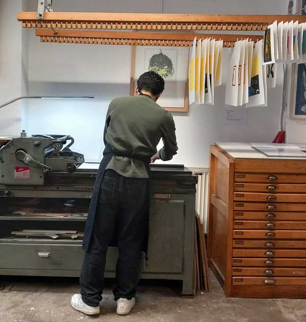 Junger Mann arbeitet an der Andruckpresse